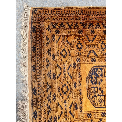 830 - A yellow ground Rug with multiple geometric borders with three stylised central motifs, 6ft 6