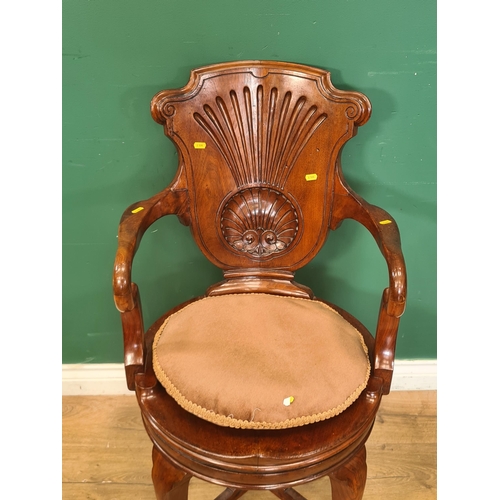 279 - A carved walnut swivel Desk Elbow Chair with fluted fan design to back, circular seat on slender cab... 