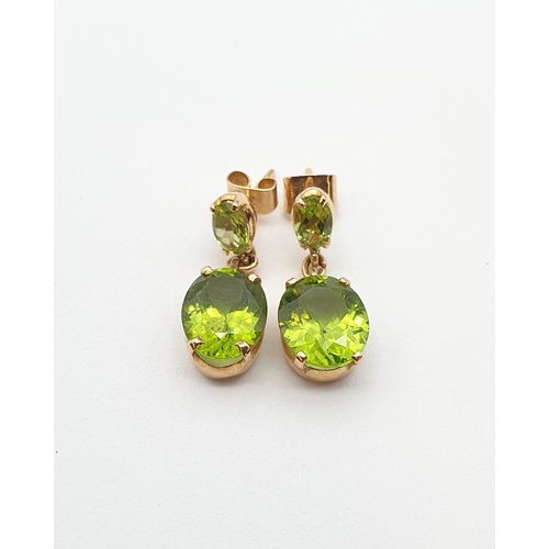 169 - A pair of Peridot drop Earrings each claw-set oval-cut stone suspending larger mixed-cut stone