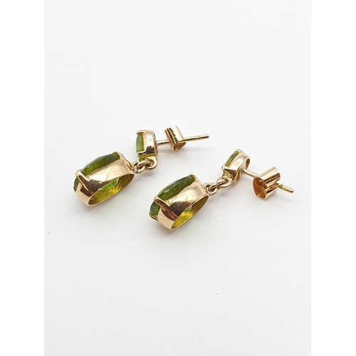 169 - A pair of Peridot drop Earrings each claw-set oval-cut stone suspending larger mixed-cut stone