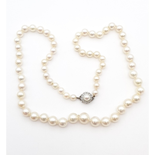 182 - A string of graduated Cultured Pearls on white metal clasp set half pearls within frame of diamonds