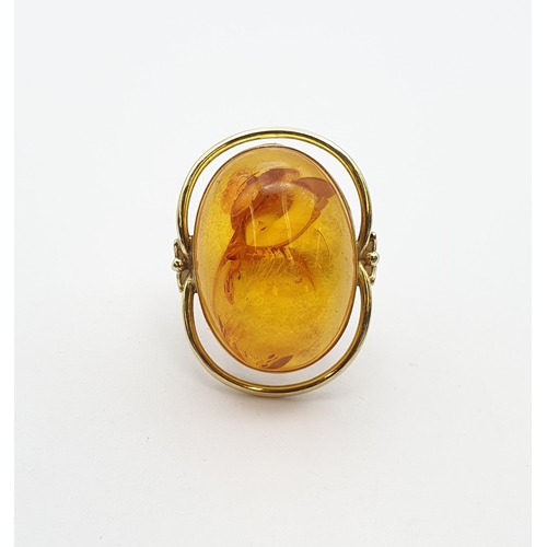 199 - A large contemporary Amber Ring set oval amber in 14ct gold halo setting, ring size Q 1/2