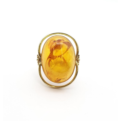 199 - A large contemporary Amber Ring set oval amber in 14ct gold halo setting, ring size Q 1/2