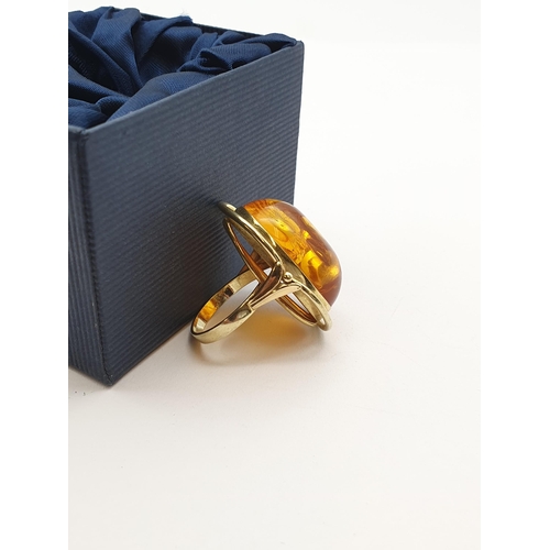 199 - A large contemporary Amber Ring set oval amber in 14ct gold halo setting, ring size Q 1/2