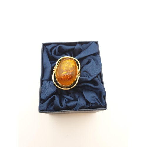 199 - A large contemporary Amber Ring set oval amber in 14ct gold halo setting, ring size Q 1/2