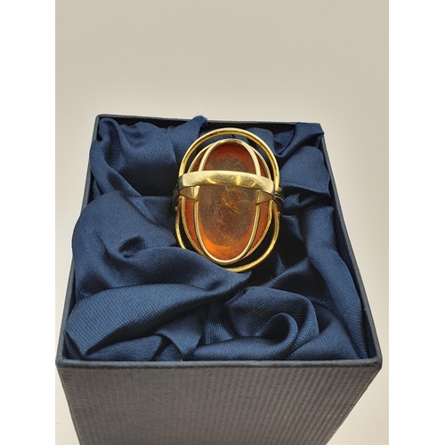 199 - A large contemporary Amber Ring set oval amber in 14ct gold halo setting, ring size Q 1/2