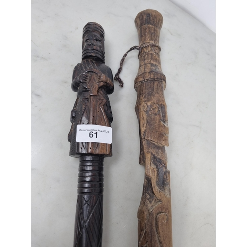 61 - Two African Tribal Walking Sticks carved figures, one holding an object, approx 3ft (R3)