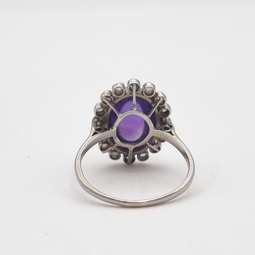 188 - *****WITHDRAWN*****

An Amethyst and Diamond Cluster Ring millegrain-set oval amethyst cabochon with... 