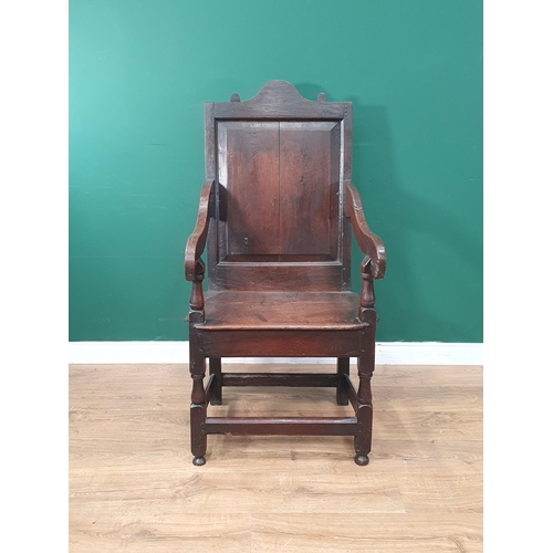 299 - A 17th Century Wainscot Elbow Chair with arched cresting to the fielded panelled back, scrolled arm ... 