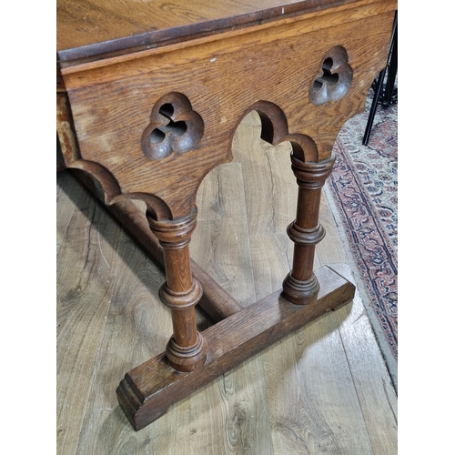 334 - A Gothic style oak Table with chamfered rectangular top, on pierced and carved ends, having turned s... 