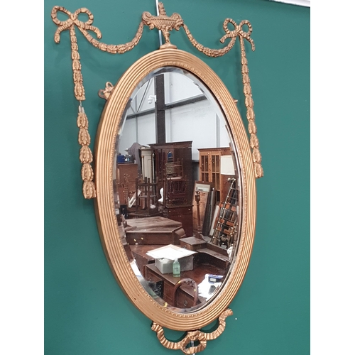 408 - A pair of Regency style gilt framed oval Wall Mirrors with urn surmounts and swag and ribbon decorat... 