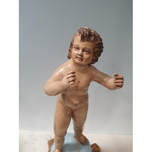 456 - A clay polychrome Figure of a Putti on square scroll base in the Rococo manner 12 1/4in H