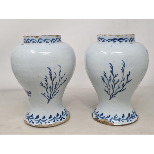 484 - A pair of Delft blue and white baluster Vases decorated with panels of flowers, 7in H