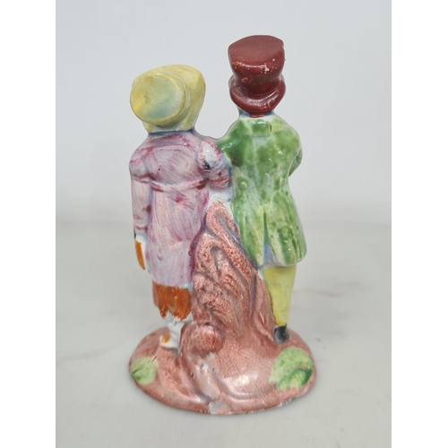 486 - A pearlware Staffordshire figure of the 'Dandies', the couple wearing red and yellow hats and long c... 