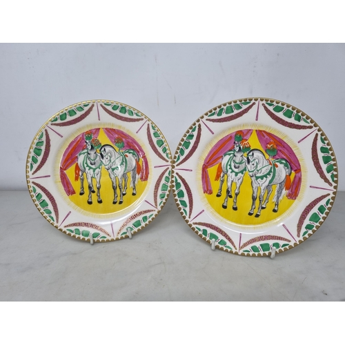 537 - A pair of Clarice Cliff Bizarre Plates, two figures of white Horses, dressed plumes on yellow ground... 