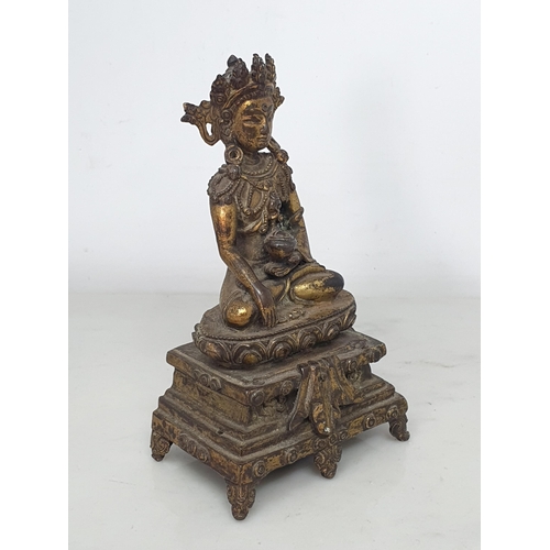 551 - An antique Nepalese gold washed bronze figure of a seated Buddha, 5 1/2in tall