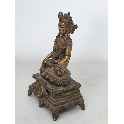 551 - An antique Nepalese gold washed bronze figure of a seated Buddha, 5 1/2in tall