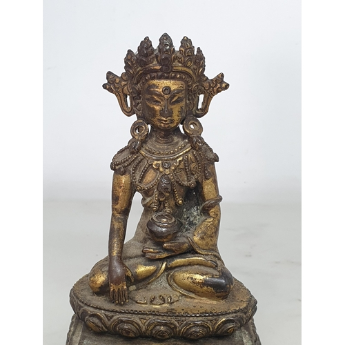 551 - An antique Nepalese gold washed bronze figure of a seated Buddha, 5 1/2in tall