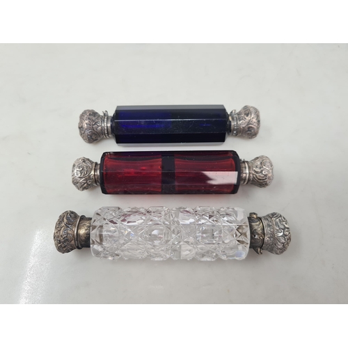 79 - Three glass double-ended Scent Bottles in red, blue and clear with floral and scroll embossed lids