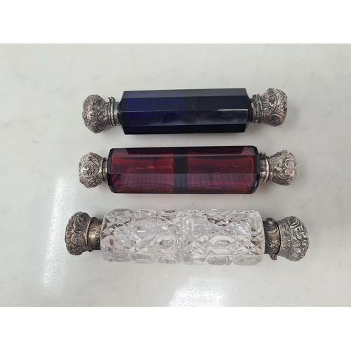 79 - Three glass double-ended Scent Bottles in red, blue and clear with floral and scroll embossed lids