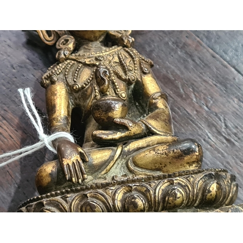 551 - An antique Nepalese gold washed bronze figure of a seated Buddha, 5 1/2in tall