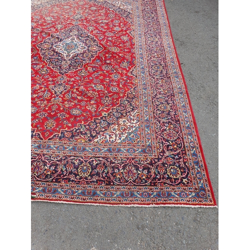 11 - A modern bordered Persian Carpet with large oval floral medallion on a red ground, palmette main bor... 