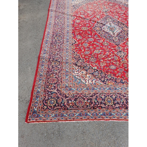 11 - A modern bordered Persian Carpet with large oval floral medallion on a red ground, palmette main bor... 