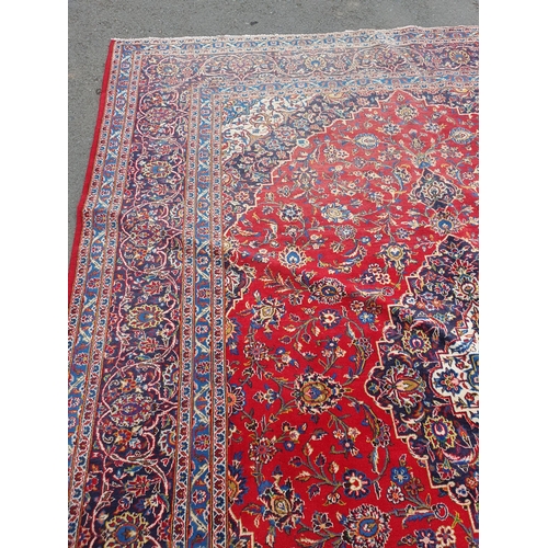 11 - A modern bordered Persian Carpet with large oval floral medallion on a red ground, palmette main bor... 