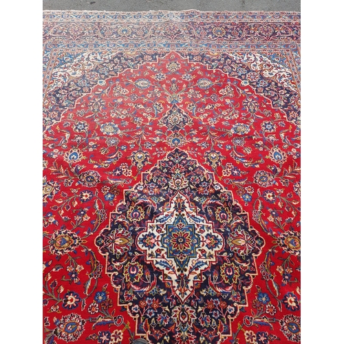 11 - A modern bordered Persian Carpet with large oval floral medallion on a red ground, palmette main bor... 