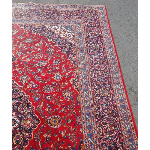 11 - A modern bordered Persian Carpet with large oval floral medallion on a red ground, palmette main bor... 