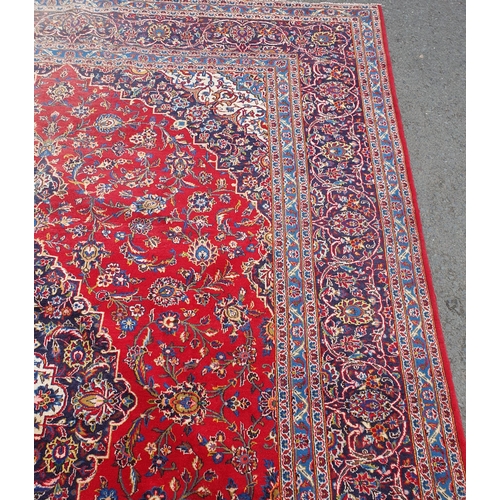 11 - A modern bordered Persian Carpet with large oval floral medallion on a red ground, palmette main bor... 