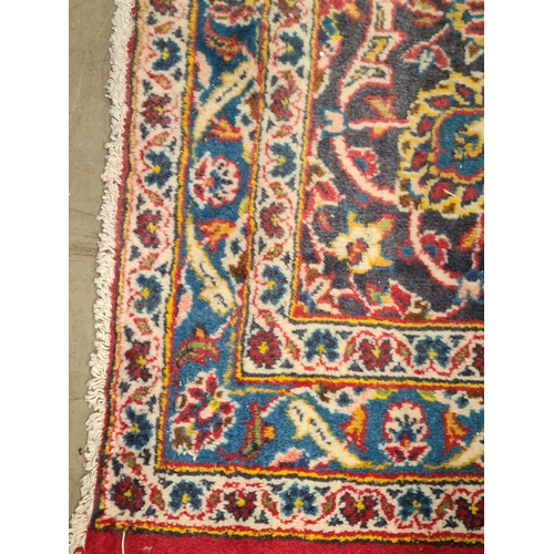 11 - A modern bordered Persian Carpet with large oval floral medallion on a red ground, palmette main bor... 