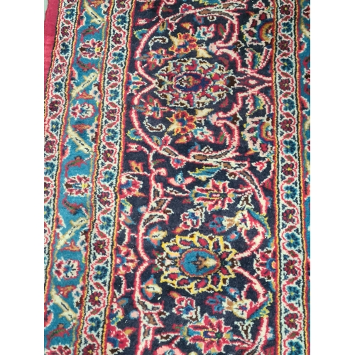 11 - A modern bordered Persian Carpet with large oval floral medallion on a red ground, palmette main bor... 