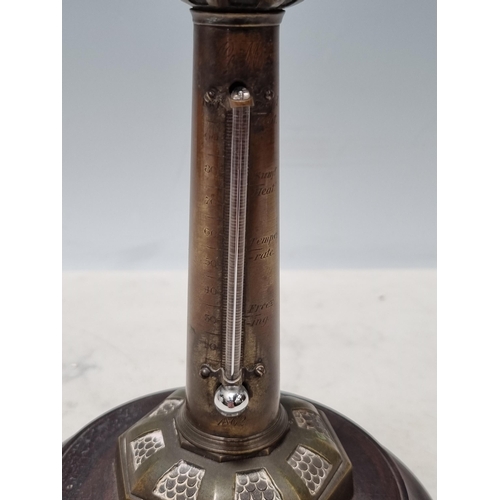 643 - An antique brass Thermometer in the form of a lighthouse with figural child finial raised on circula... 