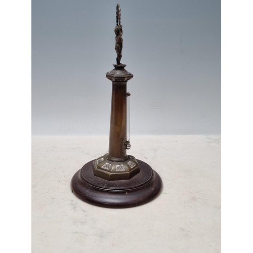 643 - An antique brass Thermometer in the form of a lighthouse with figural child finial raised on circula... 