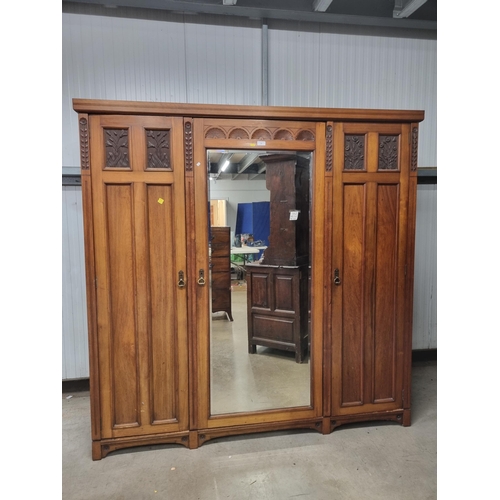 37 - An Edwardian Mirror Door Wardrobe, the moulded cornice above central mirror door, flanked by panelle... 