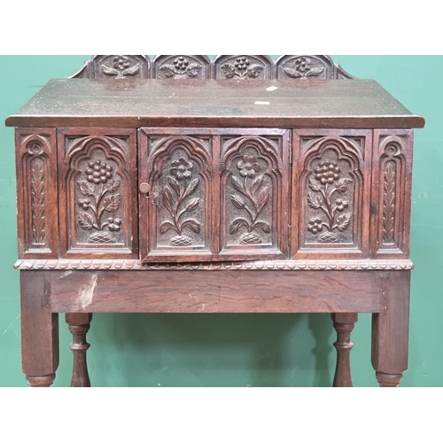 453 - A carved oak slope fronted Box fitted cupboard door to front raised on baluster turned supports and ... 