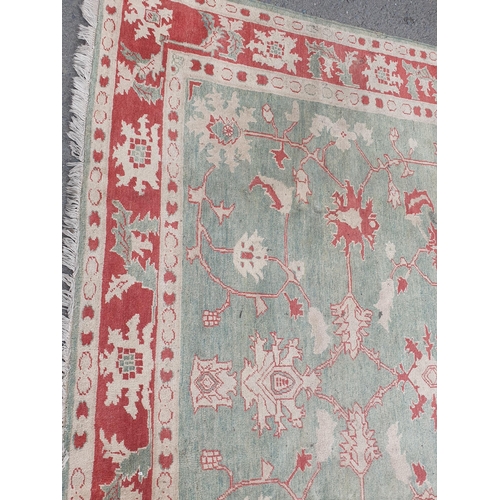 538 - A Persian style green ground Rug with trailing floral decoration within red border 8ft 7in L x 7ft 7... 