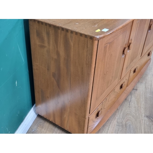 7 - An Ercol blonde elm Sideboard fitted three cupboard doors above two drawers raised on casters 4ft 3i... 