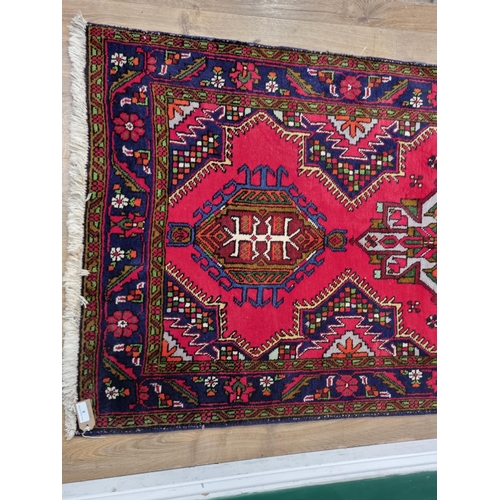 9 - A Persian style red ground woolen Runner within blue tramline border with stylised floral design 13f... 