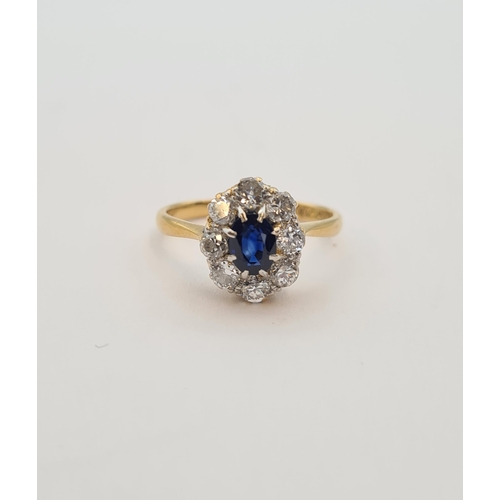 164 - A Sapphire and Diamond Cluster Ring claw-set oval-cut sapphire within a frame of eight brilliant-cut... 