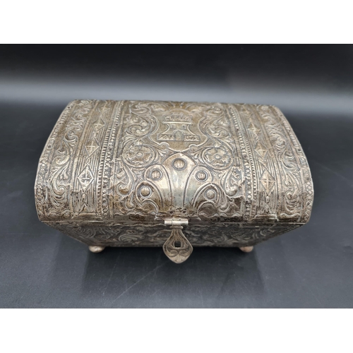 34 - A foreign silver Casket with domed lid embossed castle turret, floral and scroll surround, on turned... 