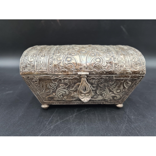 34 - A foreign silver Casket with domed lid embossed castle turret, floral and scroll surround, on turned... 