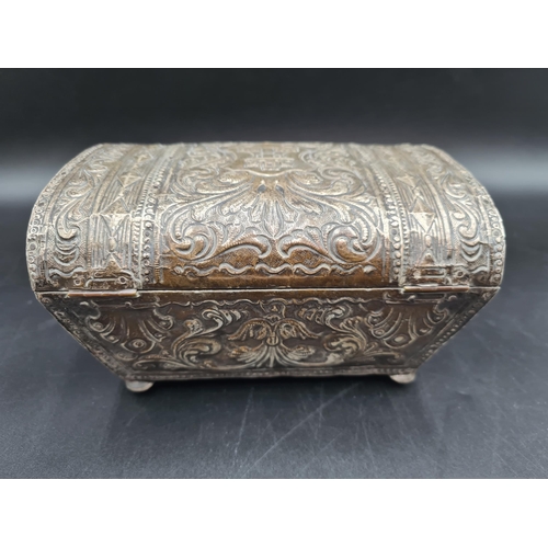 34 - A foreign silver Casket with domed lid embossed castle turret, floral and scroll surround, on turned... 