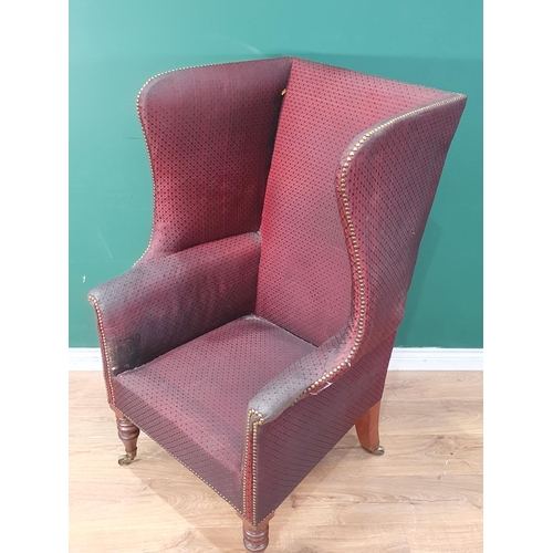 531 - A Georgian winged Armchair with burgundy studded upholstery raised on turned mahogany front supports... 