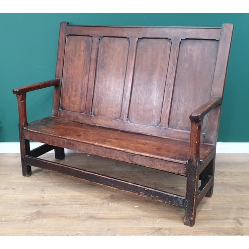 550 - A 19th Century stained pine Settle with panelled back, open arms, with two piece solid seat and rais... 