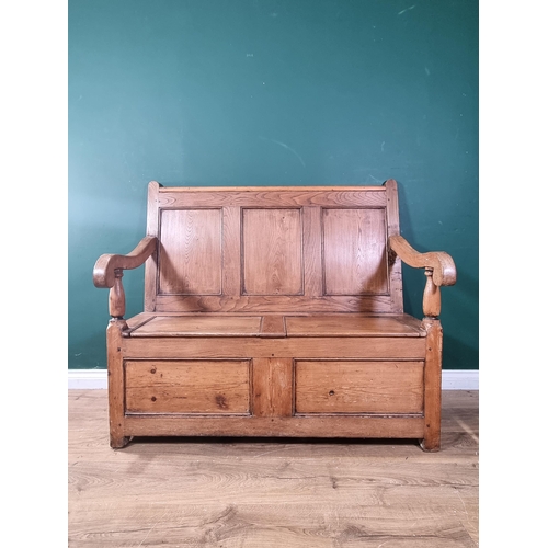 555 - An antique pine and elm Settle with panelled back, scrolled arms, double hinged box seat on square s... 