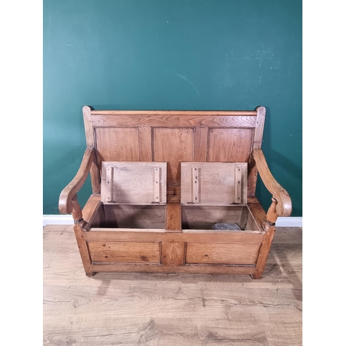 555 - An antique pine and elm Settle with panelled back, scrolled arms, double hinged box seat on square s... 