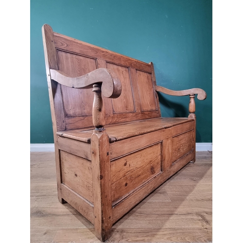 555 - An antique pine and elm Settle with panelled back, scrolled arms, double hinged box seat on square s... 