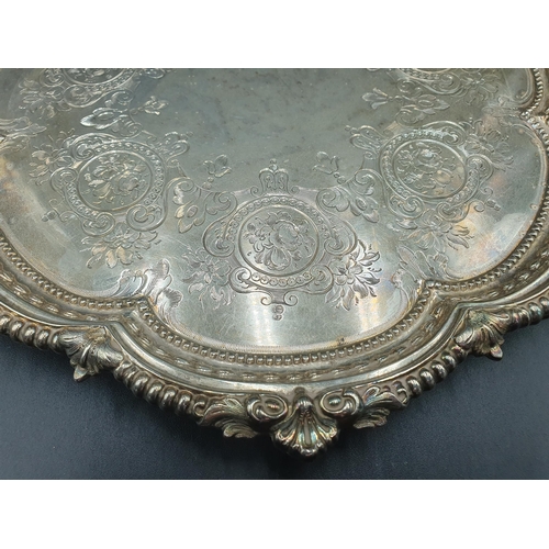 56 - A Victorian silver Salver with floral and scroll engraving, shaped rim on three ball and claw feet, ... 